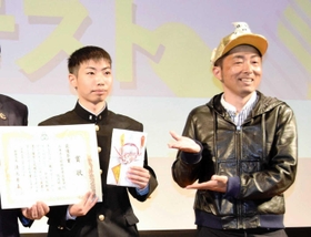 審査員の地域情報サイト編集長、ブドウちゃん（右）に祝福される姫路商業高校放送部の成田啓さん＝姫路市本町