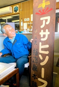 創業当時の看板を手にする小嶋昌一社長＝太子町矢田部