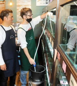 手動のポンプを使って水槽の掃除をする利用者（右）＝姫路市神屋町
