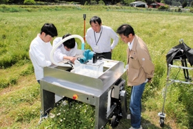 カモミール畑でロボットの動作を確認する県立大大学院の荒木望准教授（右）と森本雅和准教授（右から２人目）ら＝姫路市夢前町山之内