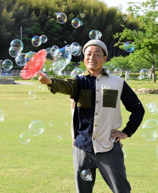 身近な道具で虹色の世界をつくり上げる「シャボン玉おじさん」＝姫路市太市中、桜山公園