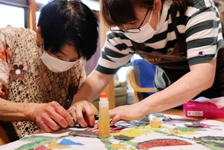 職員の助けを借りながら、ちぎり絵に取り組む利用者＝デイサービスあけびの輪