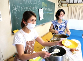 「ひだまり食堂」で子どもにカレーを盛り付ける利根川美保子さん（左）と浅田千春さん＝溝口公民館