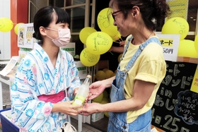 買い物客にレモネードを手渡す増田榮子さん（右）＝姫路市白銀町