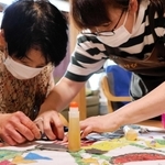 職員の助けを借りながら、ちぎり絵に取り組む利用者＝デイサービスあけびの輪