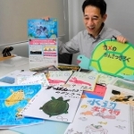 コンテストに寄せられた過去の作品を前に、応募を呼びかける田部勉さん＝姫路市白銀町、キョーリン
