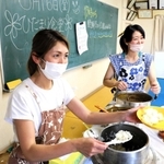 「ひだまり食堂」で子どもにカレーを盛り付ける利根川美保子さん（左）と浅田千春さん＝溝口公民館