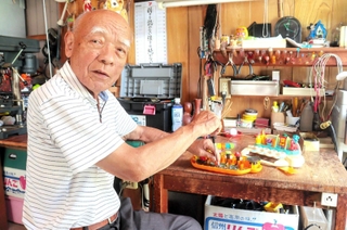 自宅ガレージでおもちゃの修理を続ける吉田清彦さん＝姫路市東今宿