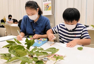 じっくり観察し、サクラの葉を描く親子ら＝姫路文学館
