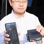 スマホと連動した車両盗難防止装置「スマートガード」を持つ服部喜優さん＝コアテックシステム