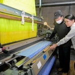 再稼働したジャカードカラミ織り機を見つめる大塚美智代さん（右）と藤原博明社長＝西脇市中畑町