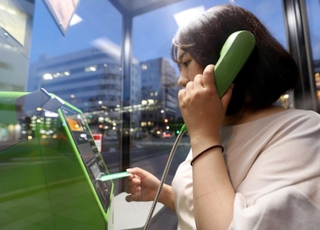 公衆電話を使う橘高声記者。なんだか見られている気分…＝姫路市内（撮影・辰巳直之）