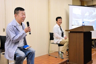 西島の写真を示しながら、物語の背景について説明する鄭義信さん（左）＝姫路市総社本町
