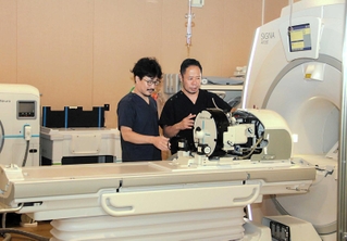 脳に超音波を当てる治療機器を説明する川上太一郎医師（右）ら＝姫路市網干区和久