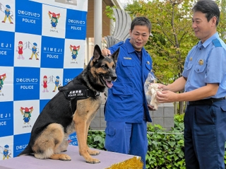 白野邦昌署長からからおもちゃをもらい喜ぶムック号と門脇正真警部補＝姫路署