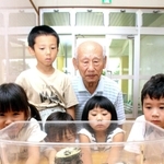 塩山顕治さん（後列右）と、スズムシの音色を楽しむ園児たち＝福崎町福崎新