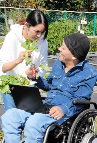 遠隔で育てた野菜の出来を、妻桂子さんと確認する有末翔太さん＝姫路市船津町
