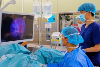 光線力学診断を取り入れ、ぼうこうがんの内視鏡手術をする医師たち。病変が赤く発光している（姫路赤十字病院提供）