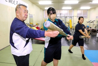 神田吉輝監督（左端）からスイングを教わる高畑采美さん（中央）、矢野彩星さん＝姫路別所高