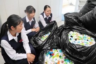 集まったペットボトルキャップと回収に取り組んだ城山中学校の生徒たち＝姫路市飾東町豊国