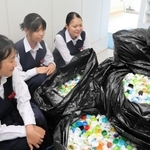 集まったペットボトルキャップと回収に取り組んだ城山中学校の生徒たち＝姫路市飾東町豊国