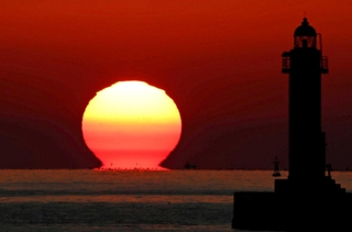 だるまの頭のように変形しながら水平線に沈む夕日＝姫路市飾磨区の中島埠頭から南西方向を望む