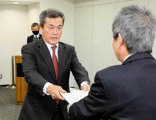 西田耕太郎教育長に報告書を手渡す学校地域協議会の畑野長利会長（左）＝姫路市役所北別館