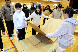 体育館で段ボールベッドを組み立てる児童ら＝坊勢小学校