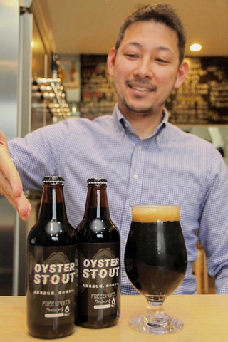 赤穂市産のカキを使った黒ビールを紹介する宮崎隼人さん＝姫路市久保町