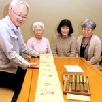 福山藍子さん（右から２人目）が寄贈した巻物を広げて見る学芸員の工藤茂博さん（左端）ら＝姫路市本町