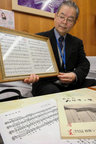 校歌の古い楽譜を見つけた黒田裕治校長＝城山中学校