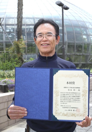 「木村賞」の表彰状を手に喜ぶ手柄山温室植物園の松本修二さん＝姫路市手柄