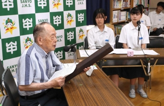 焼夷弾の実物を手に戦争体験を中学生に伝える黒田権大さん（左）＝山陽中学校