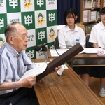 焼夷弾の実物を手に戦争体験を中学生に伝える黒田権大さん（左）＝山陽中学校