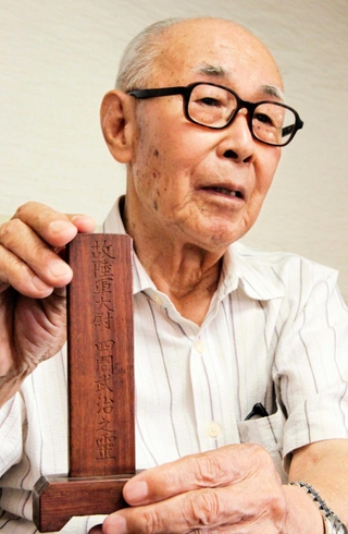 四間隊の生還者が作った武治さんの位牌を手に、父への思いを語る四間一哉さん＝和歌山市西浜