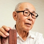 四間隊の生還者が作った武治さんの位牌を手に、父への思いを語る四間一哉さん＝和歌山市西浜