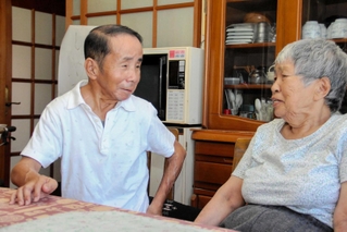 認知症が進む母文子さん（右）を自宅で介護する小林延也さん。親子での会話を大切にする＝姫路市林田町林谷