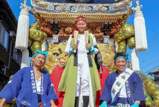 祖父の宮田浩さん（左）、叔父の朋英さん（右）も着用した衣装で、太鼓をたたく乗り子を務める田代銀冬さん（中央）＝武大神社
