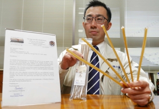 ブータンから受け取った感謝状を前に、「三千本にかわ」を手にする旭陽化学工業の田寺宣文社長＝姫路市網干区福井