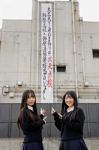 小西佑菜さん（右）と上田芽郁さんが制作した火災への備えを呼びかける懸垂幕＝飾磨消防署