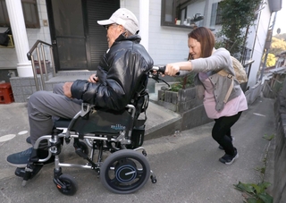車いすを押しながら急坂を上り、高齢男性を自宅まで送り届ける片山美紀子さん＝姫路市家島町真浦