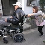 車いすを押しながら急坂を上り、高齢男性を自宅まで送り届ける片山美紀子さん＝姫路市家島町真浦
