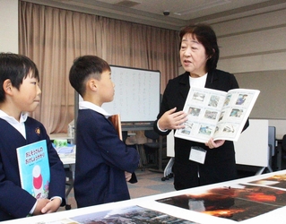 新聞の切り抜きや絵本で備えの大切さを伝える谷智子さん（右）＝福崎町西田原