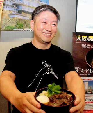 大阪・関西万博の会場で提供する「究極のえきそば」を手に、意気込みを語るまねき食品の竹田典高社長＝姫路市北条