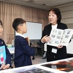 新聞の切り抜きや絵本で備えの大切さを伝える谷智子さん（右）＝福崎町西田原