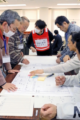 ひめじ防災マイスター（左から３番目）のアドバイスを受けながら図上訓練に取り組む住民ら＝姫路市大津区天満
