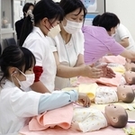 看護師になりきり、人形に聴診器を当てる子どもたち＝姫路独協大学