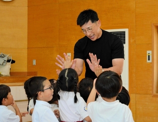 ハイタッチをして園児たちと触れ合う矢野燿大さん＝姫路市豊富町豊富、萩学園