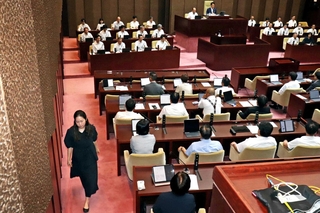辞職勧告決議案の採決を前に退席する姫路市議会の高見千咲議員（左）＝３０日午前、姫路市役所