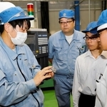金属部品を手に、新興精機製作所の作業員（左）から技を学ぶ飾磨工業高校の生徒ら＝姫路市阿保